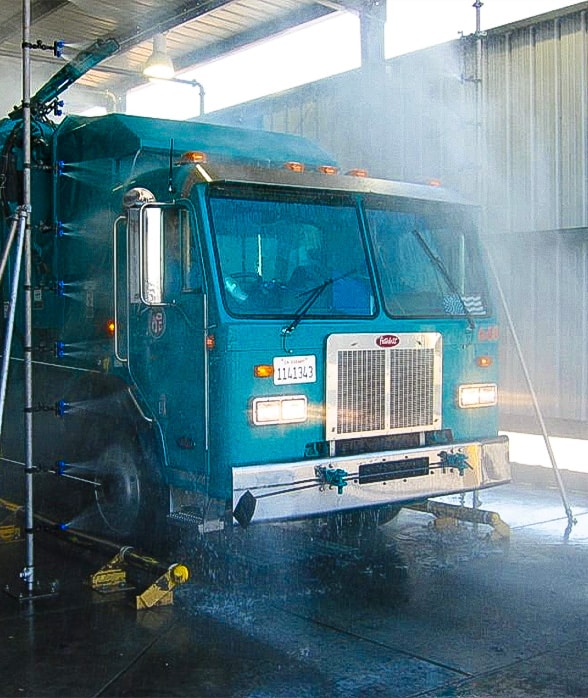 Blue dump truck going through automatic drive-through wash system