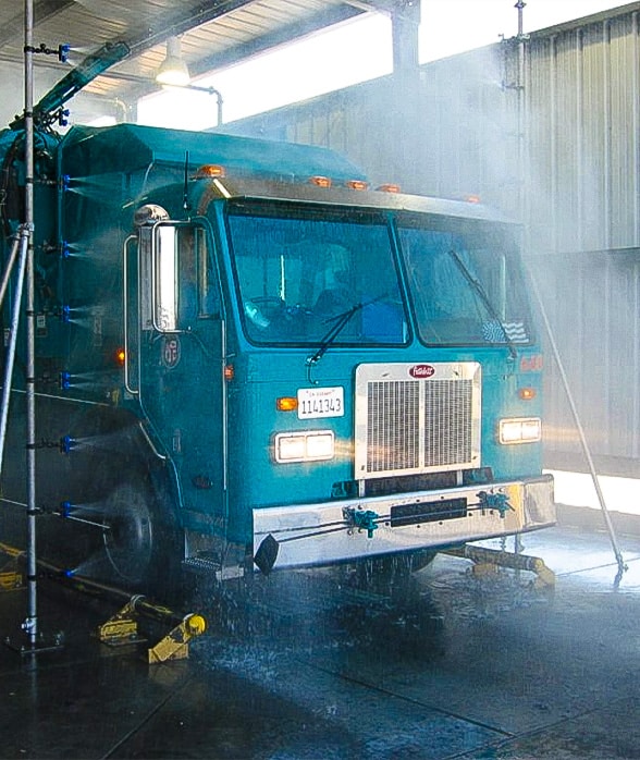 Blue dump truck going through automatic drive-through wash system
