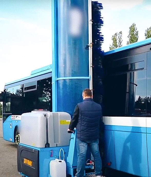 Man operating single brush wash system to clean bus