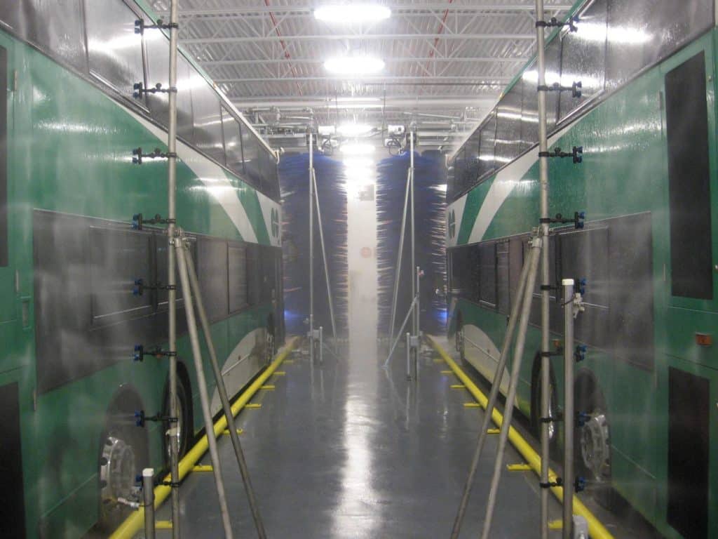 Two green buses in wash bays cleaning their fleet with an InterClean wash system.