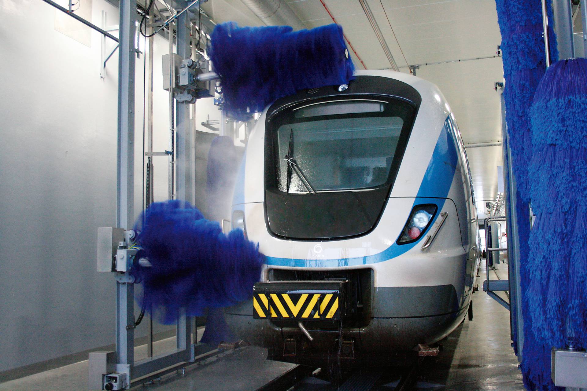 InterClean brush wash system cleaning a white and blue train.
