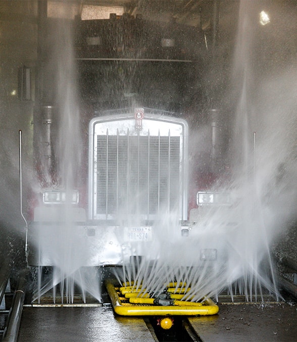 Heavy-duty truck driving through wheel wash system