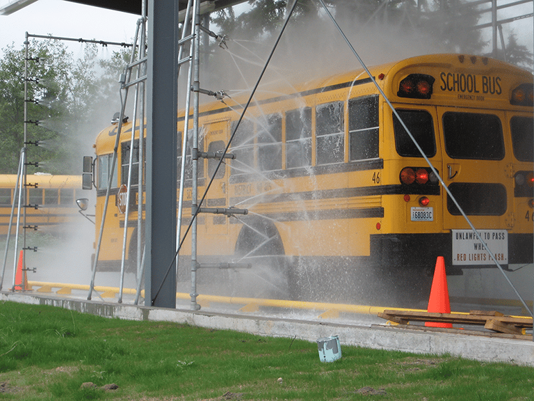 Yellow school bus being cleaned by touchless wash system