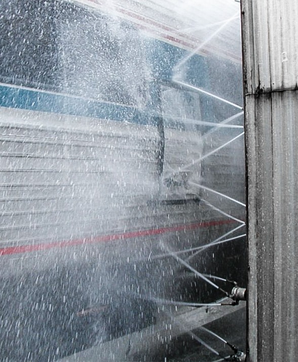 A train getting sprayed with water and detergents.