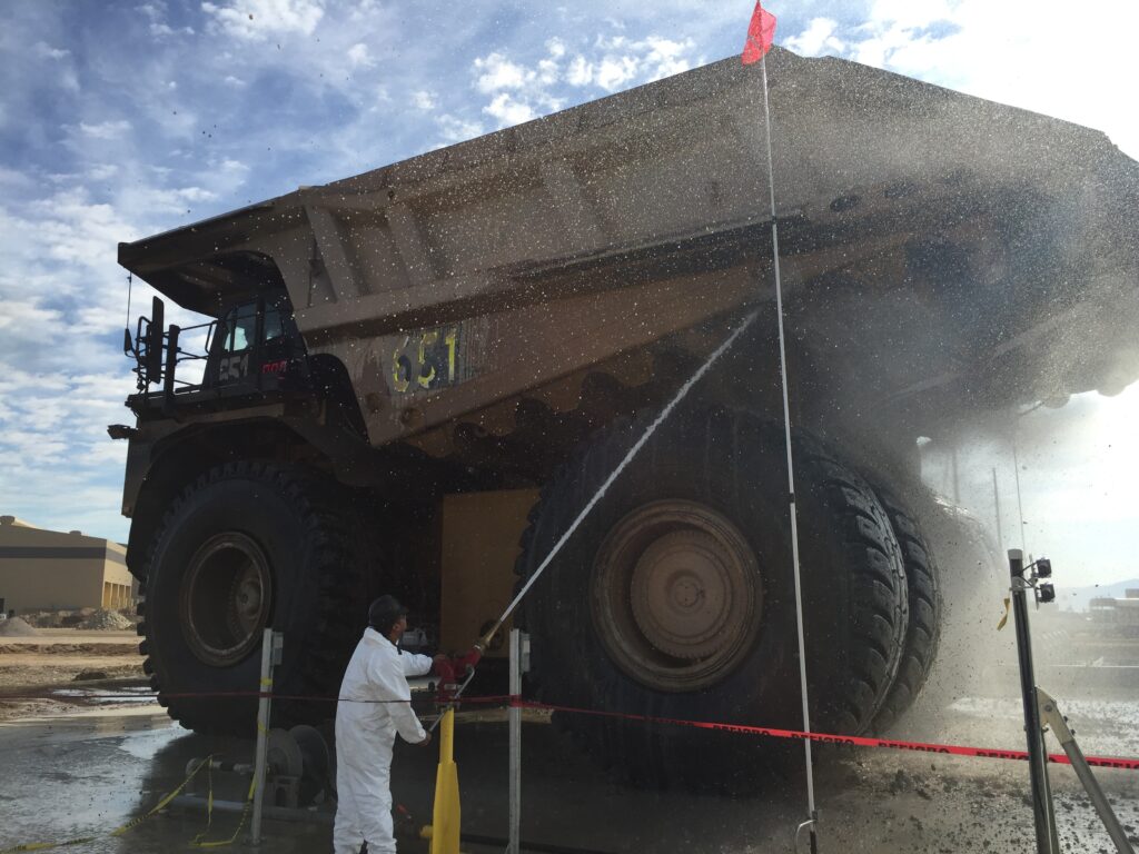 Man using mounted wash man to power wash industrial vehicle