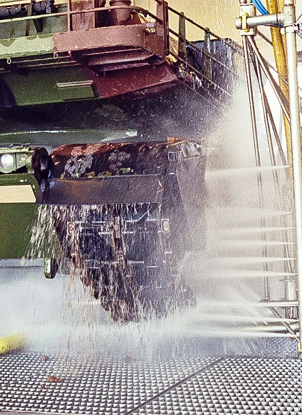 A tank driving through military vehicle wash equipment.