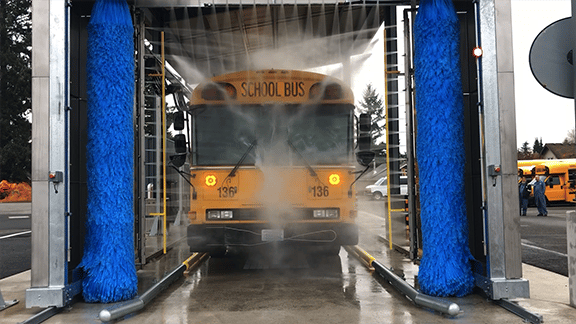 School bus going through 3 brush rollover gantry with V-spray