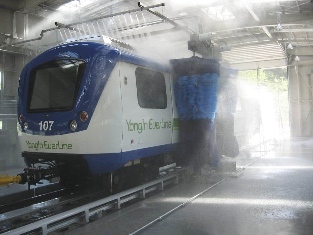 Blue and white LRT train being washed in drive-through wash system