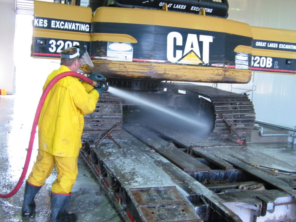 Excavator having tracks washed manually with jet stream by worker
