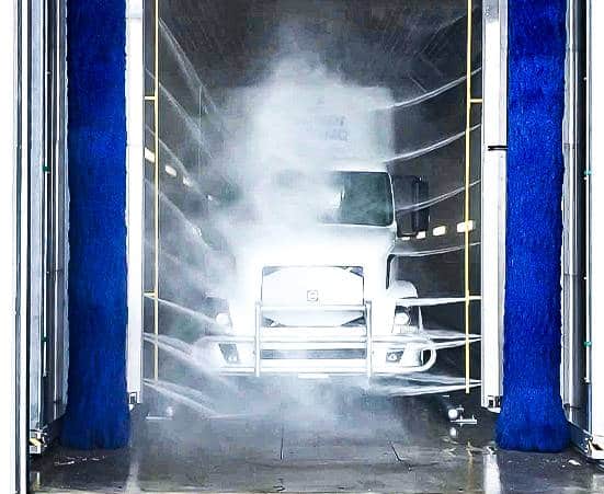 Fleet vehicle being washed with drive-through wash system
