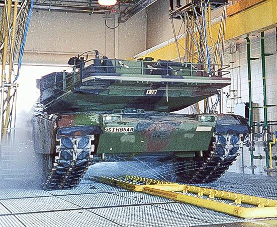 Large military tank being washed with drive-through system