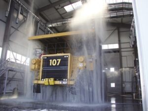 Large yellow mining vehicle going through automatic wash system