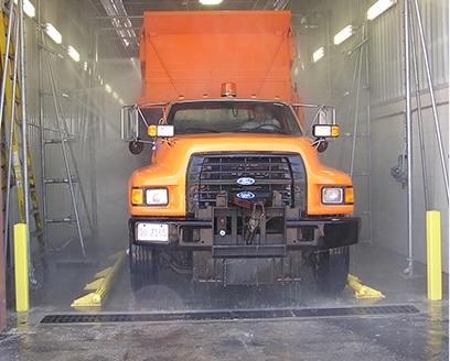 Large orange truck inside truck wash system