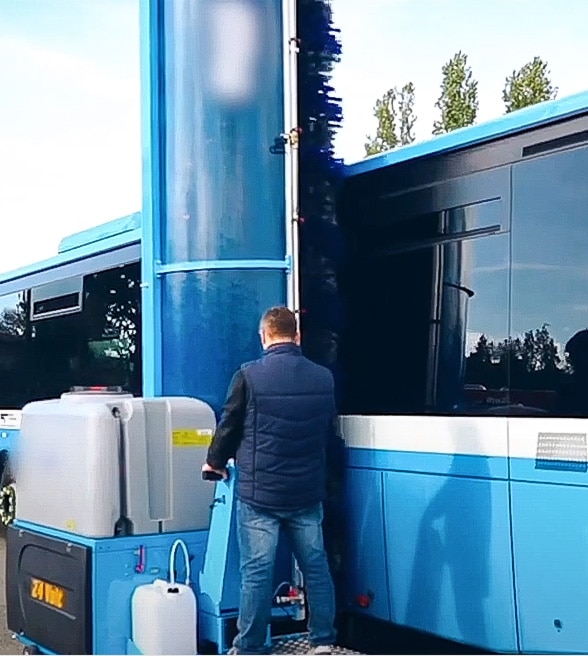 Someone cleaning bus with single brush manual wash system