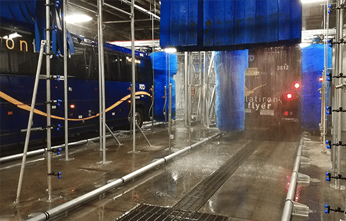 Bus moving through two lane friction wash system