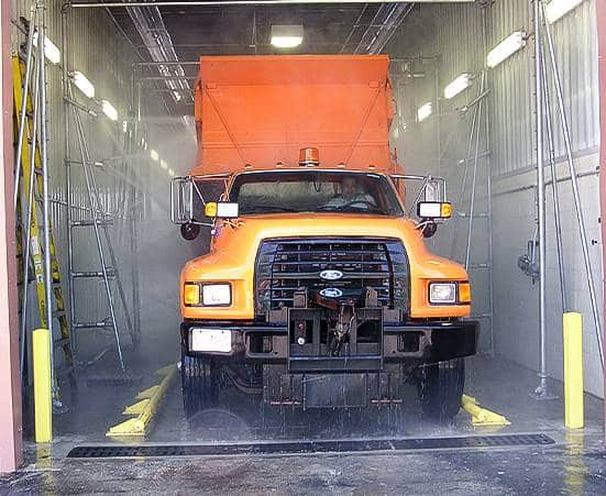 An orange truck going through a fleet wash system.