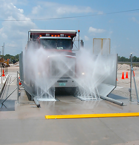 A truck being sprayed with water in a truck wash system.