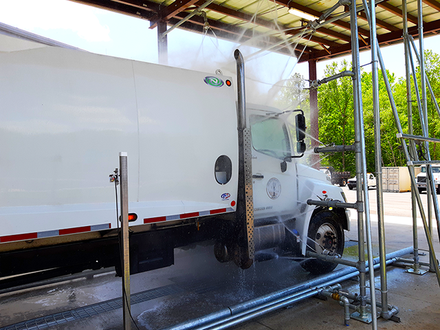 A white truck going through a truck wash system.