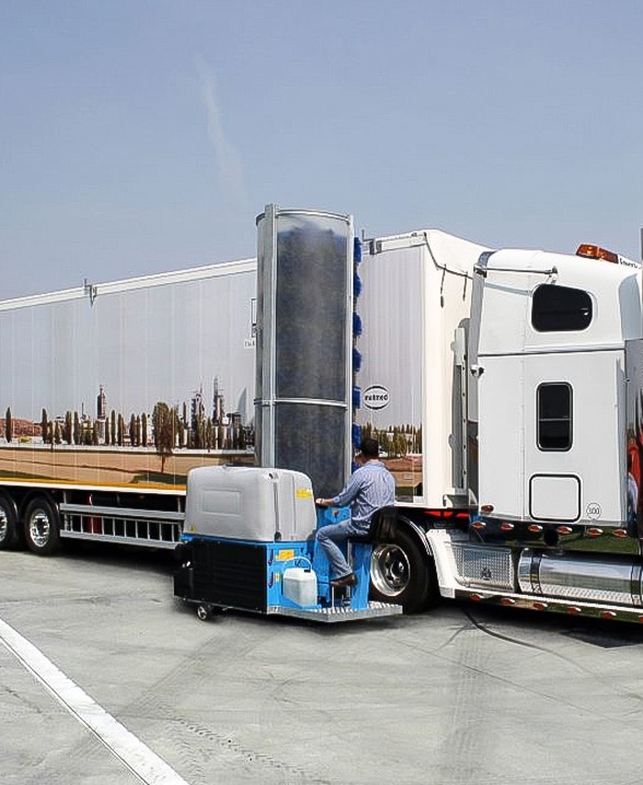 A person washing a commercial truck with a truck wash system.