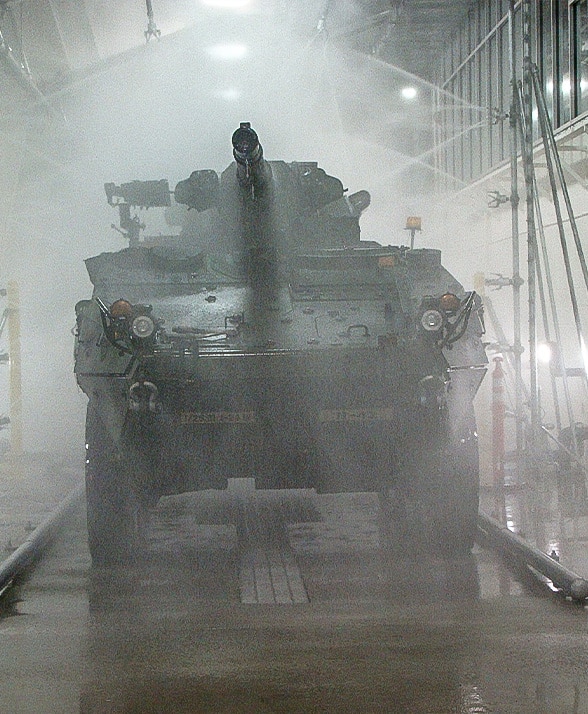 A tank driving through a military vehicle wash system.