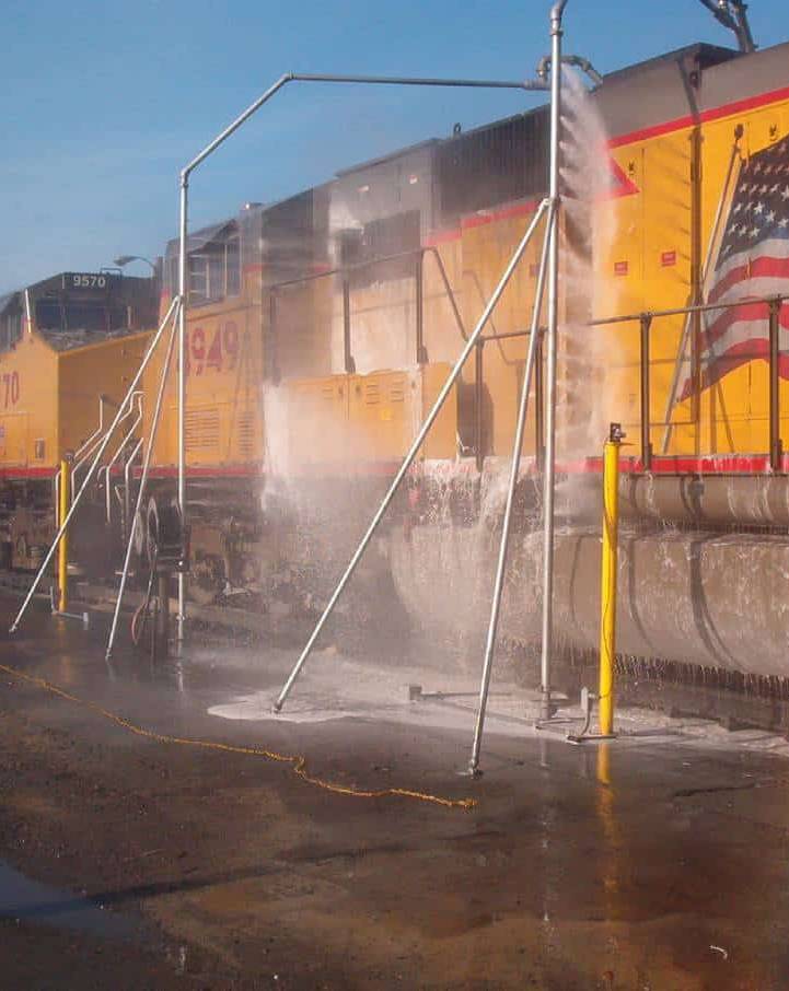 A yellow train being washed by a train car wash.