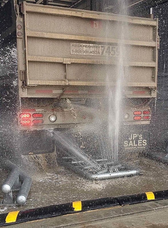 A large vehicle being washed by a heavy vehicle wash system.